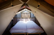 Soveområde i Air Lodge ved Hoge Kempen i Belgien, med to enkeltsenge og bløde, hvide lagner i et telt.