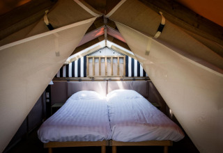 Espace nuit à l’Air Lodge du Hoge Kempen en Belgique, avec deux lits simples et draps blancs sous une tente.