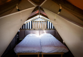 Espace nuit à l’Air Lodge du Hoge Kempen en Belgique, avec deux lits simples et draps blancs sous une tente.