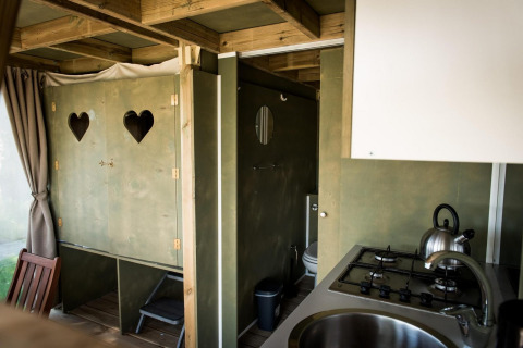 Vista interior de Air Lodge en Hoge Kempen, Bélgica, con cocina, baño y decoración de madera acogedora.