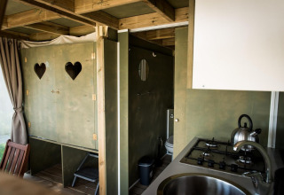 Vista interior de Air Lodge en Hoge Kempen, Bélgica, con cocina, baño y decoración de madera acogedora.