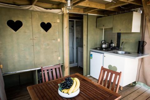 Interiør af Air Lodge på Hoge Kempen i Belgien med et lille køkken, spisebord og skab med hjerteformede vinduer.