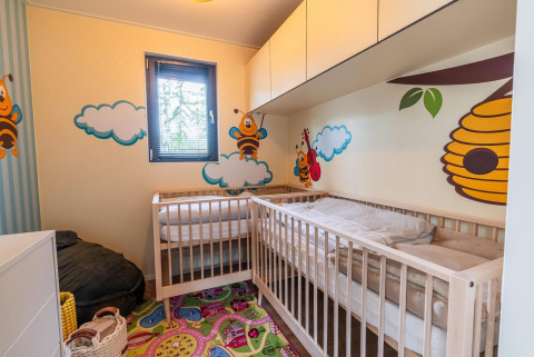 Buntes Kinderzimmer mit Gitterbetten, Bienen- und Wolkenmotiven im Baby cottage, Hoge Kempen, Belgien.
