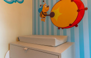 Et puslebord med en skummåtte foran en væg med et tegn på en bi der spiller på en tromme i Baby Cottage.