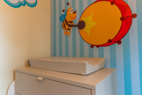 Et puslebord med en skummåtte foran en væg med et tegn på en bi der spiller på en tromme i Baby Cottage.