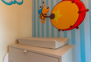 Changing table with foam pad in Baby Cottage at Hoge Kempen, Belgium, with bee and drum wall art.