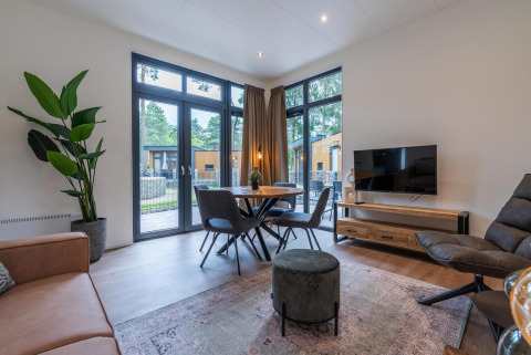 Moderne stue i Baby cottage ved Hoge Kempen, Belgien, med store vinduer, spisebord og grønne planter.