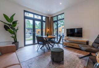 Moderne stue i Baby cottage ved Hoge Kempen, Belgien, med store vinduer, spisebord og grønne planter.