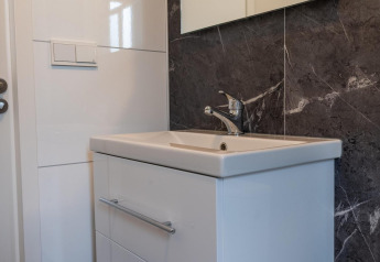 Lavabo moderno con mobile bianco e parete effetto marmo nel Baby Cottage a Hoge Kempen, Belgio.