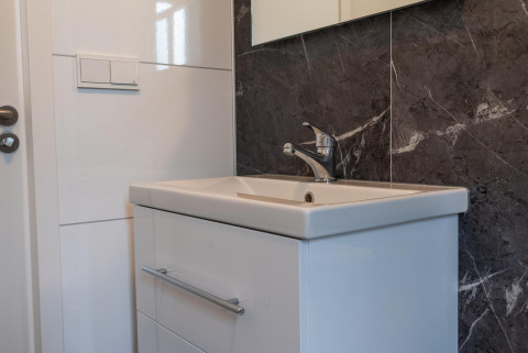 Modern bathroom sink with white vanity and marble wall in Baby Cottage at Hoge Kempen, Belgium.