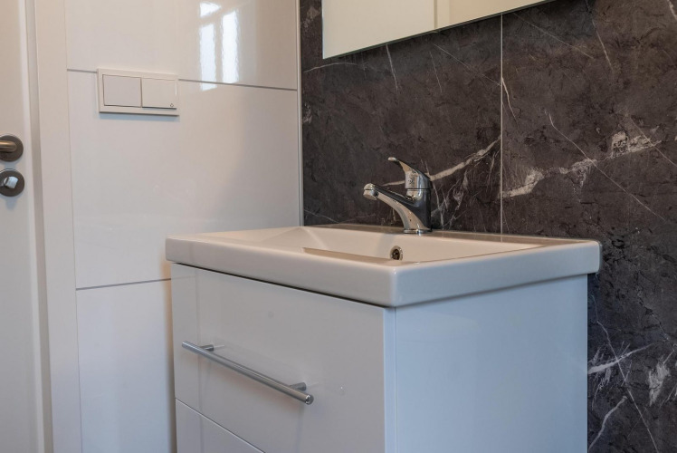 Lavabo moderno con mueble blanco y pared de mármol en Baby Cottage en Hoge Kempen, Bélgica.