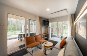 Salon du lodge Belsano à Hoge Kempen, Belgique, avec mobilier moderne et vue sur la forêt extérieure.
