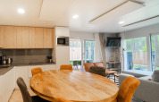 Moderne woonkamer en keuken in een Belsano-lodge te Hoge Kempen, België, met houten interieur en ramen.