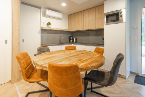Modern kitchen and dining area at Belsano lodge in Hoge Kempen, Belgium, with a wooden round table and chairs.