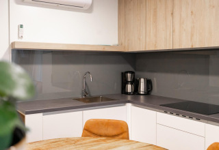 Cocineta moderna en el lodge Belsano en Hoge Kempen, Bélgica, con cafetera y gabinetes de madera.