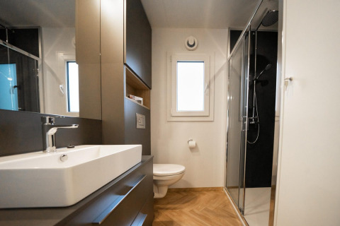 Baño moderno en la Belsano lodge de Hoge Kempen, Bélgica, con ducha acristalada y suelo de madera clara.