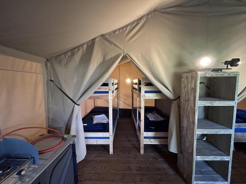 Interno della tenda safari Bergerven Lodge ad Hoge Kempen in Belgio con letti a castello e scaffali in legno.