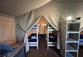 Interno della tenda safari Bergerven Lodge ad Hoge Kempen in Belgio con letti a castello e scaffali in legno.