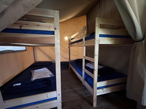 Vista interior de la tienda safari Bergerven Lodge en Hoge Kempen, Bélgica, con literas y suelo de madera.