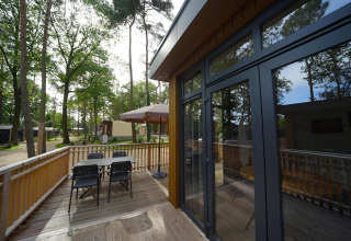Buitenterras aan tiny house Cube La Mer in Hoge Kempen, België met tafel, stoelen en grote parasol.
