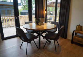 Comedor moderno con mesa redonda y cuatro sillas dentro de la tiny house Cube La Mer en Hoge Kempen, Bélgica.