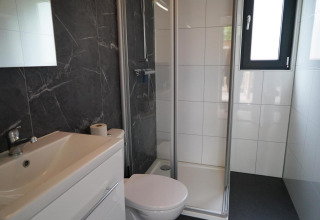 Bagno moderno con doccia, wc e lavabo nella tiny house Cube La Mer a Hoge Kempen, Belgio.