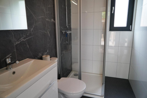 Moderne badkamer met douche, toilet en wastafel in Cube La Mer tiny house te Hoge Kempen, België.