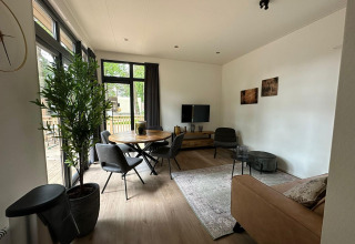 Soggiorno moderno nella tiny house Cube La Mer a Hoge Kempen, Belgio, con ampie finestre e arredo accogliente.