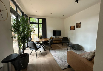 Soggiorno moderno nella tiny house Cube La Mer a Hoge Kempen, Belgio, con ampie finestre e arredo accogliente.