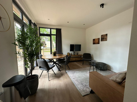 Salon moderne de la tiny house Cube La Mer à Hoge Kempen, Belgique, avec grandes fenêtres et déco chaleureuse.