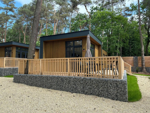 Moderne Cube La Mer Tiny House mit Holzterrasse im Wald, gelegen im Hoge Kempen, Belgien.
