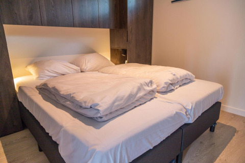 Modernes Doppelbett mit weißer Bettwäsche im Forest Cottage, einem Tiny House in Hoge Kempen, Belgien.
