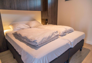 Letto matrimoniale moderno con biancheria bianca nel Forest Cottage, tiny house a Hoge Kempen, Belgio.