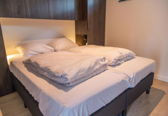 Modern tweepersoonsbed met wit beddengoed in Forest Cottage, een tiny house in Hoge Kempen, België.