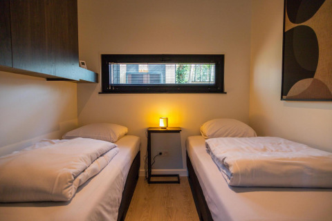 Gemütliches Schlafzimmer mit zwei Einzelbetten im Forest Cottage, Hoge Kempen, Belgien, moderne Einrichtung.