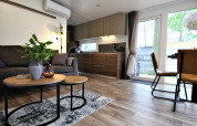Moderne leefruimte en keuken in Kempen cottage, Hoge Kempen, België, met houtaccenten en grote ramen.