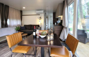 Salón y comedor moderno en la cabaña Kempen Cottage en Hoge Kempen, Bélgica, con vistas naturales desde grandes ventanales.