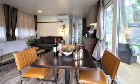 Salón y comedor moderno en la cabaña Kempen Cottage en Hoge Kempen, Bélgica, con vistas naturales desde grandes ventanales.