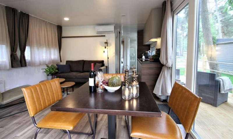 Salón y comedor moderno en la cabaña Kempen Cottage en Hoge Kempen, Bélgica, con vistas naturales desde grandes ventanales.