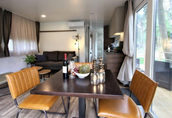 Salón y comedor moderno en la cabaña Kempen Cottage en Hoge Kempen, Bélgica, con vistas naturales desde grandes ventanales.