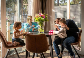 Familie sitzt zusammen in einem Kempen Cottage am Hoge Kempen in Belgien und genießt eine gemeinsame Mahlzeit.