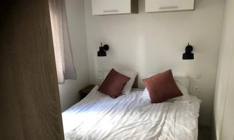 Tweepersoonsbed met witte lakens en twee bruine kussens in Kempen cottage, Hoge Kempen, België.