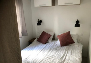 Cama doble con sábanas blancas y dos cojines marrones en la Kempen cottage en Hoge Kempen, Bélgica.