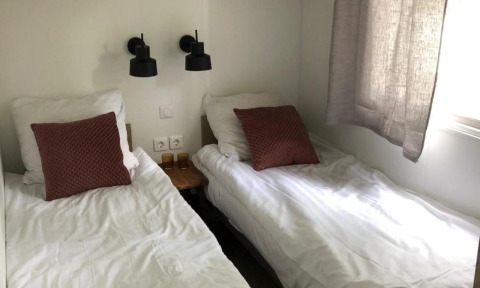 Dos camas individuales con sábanas blancas y cojines marrones en Kempen cottage, Hoge Kempen, Bélgica.