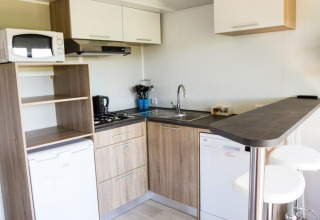 Cucina moderna al Kempen cottage di Hoge Kempen, Belgio, con elettrodomestici, bancone e sgabelli.