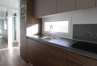 Cocina moderna en Kempen cottage en Hoge Kempen, Bélgica, con armarios de madera y ventana grande.