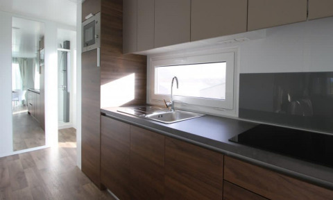 Cucina moderna in Kempen cottage a Hoge Kempen, Belgio, con armadi in legno e ampia finestra.