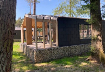 Panorama Cottage, una tiny house moderna con pareti in vetro e terrazza, immersa tra gli alberi.