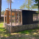 Panorama Cottage, et lille hus med moderne glasfacade og terrasse, omgivet af træer i sollys.