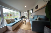 Lyst og hyggeligt opholdsområde i Panorama Cottage, et tiny house i Hoge Kempen, Belgien, med store vinduer.